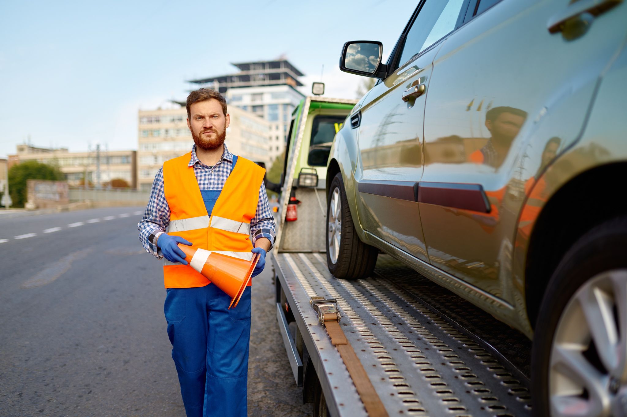 a person in a vest and gloves holding a cone next to a car