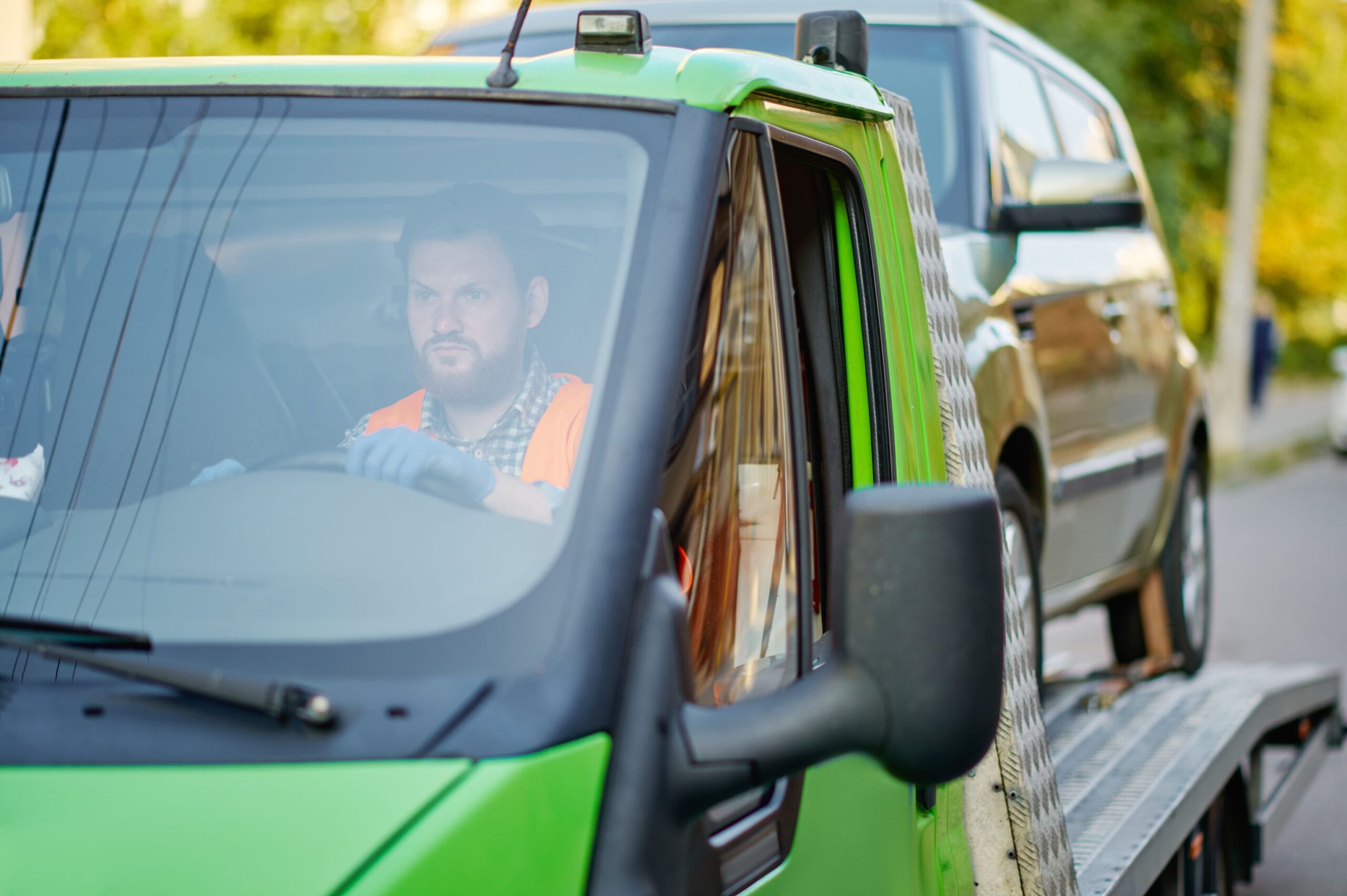 a person in a vest and gloves holding a cone next to a car